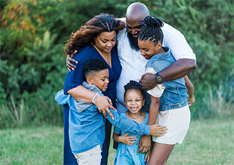 A family hugging and laughing at the park