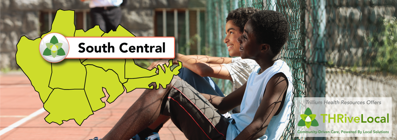  Two teen boys friends sitting on a basketball court laughing