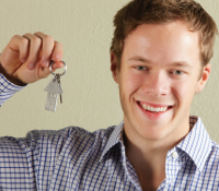 young man smiling holding a key