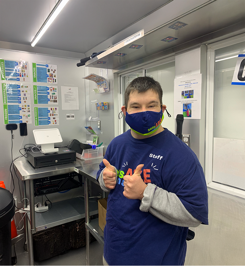 A young man with a face mask and signing thumb up