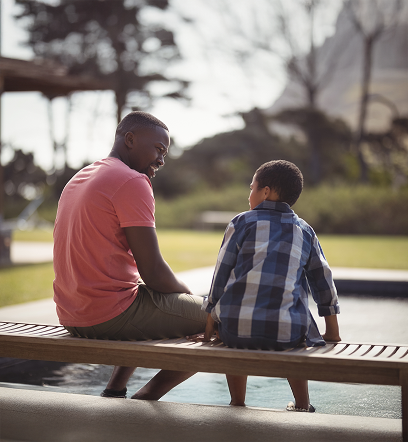 A father and son sitting on a park bench
