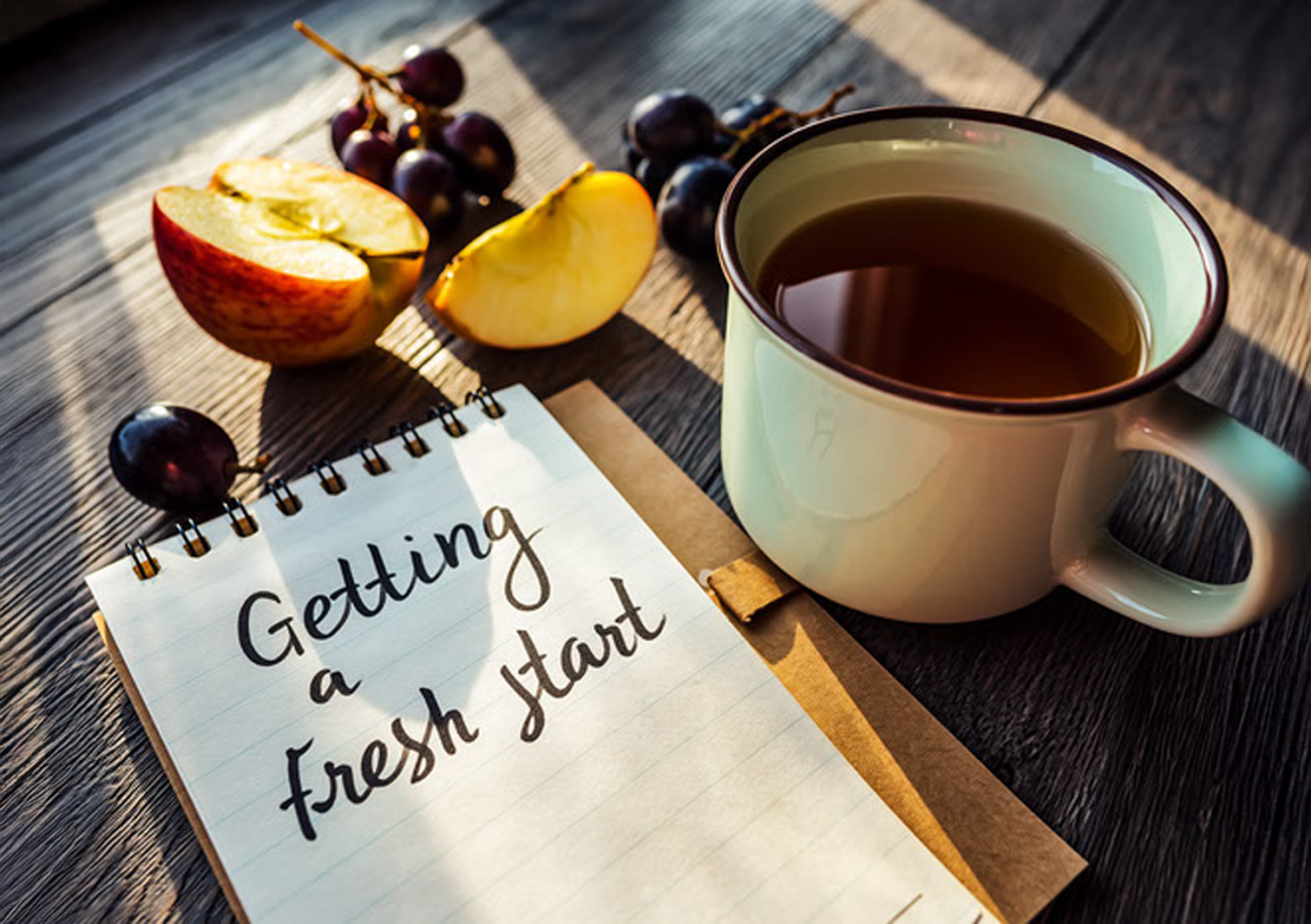 A photo with a notepad, a cup of tea, and fruits