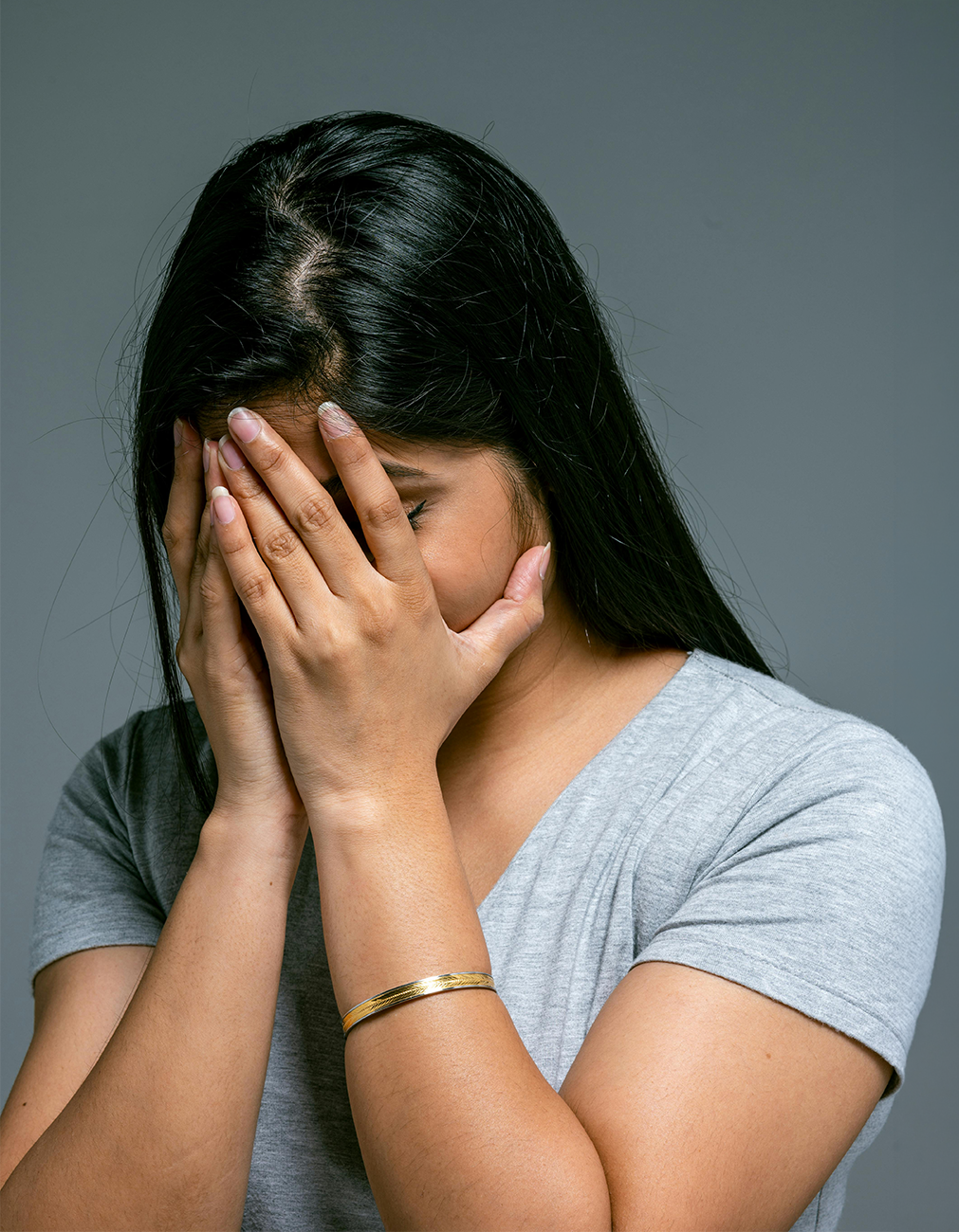 A young woman covering her face looking in distress