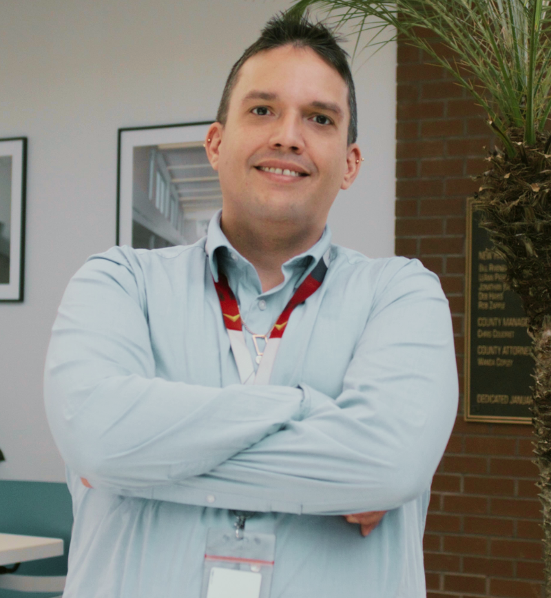 A man looking at the camera posing confidence with arm crossed and smiling